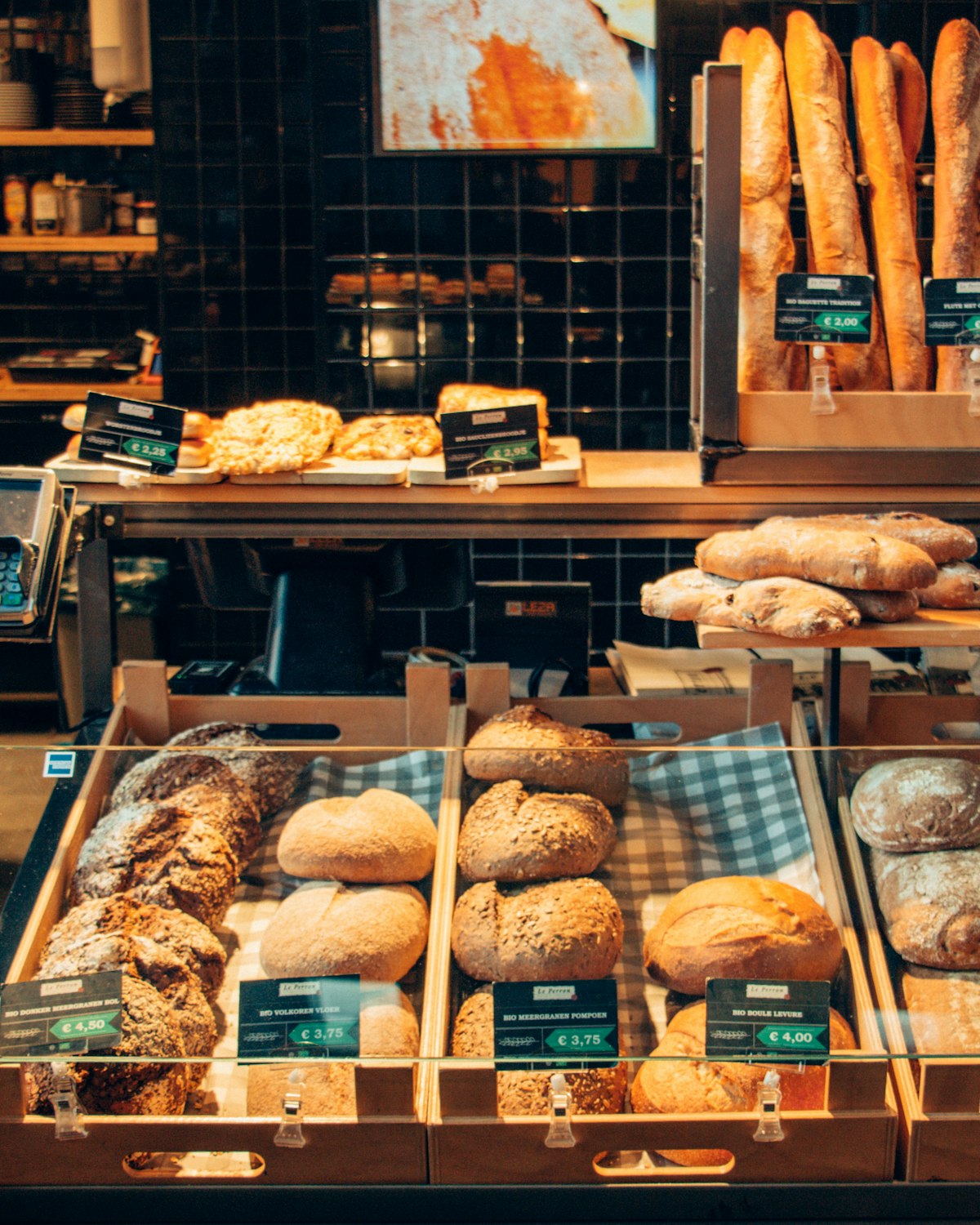 A busy Au Gourmand market stall stacked with loaves and pastries