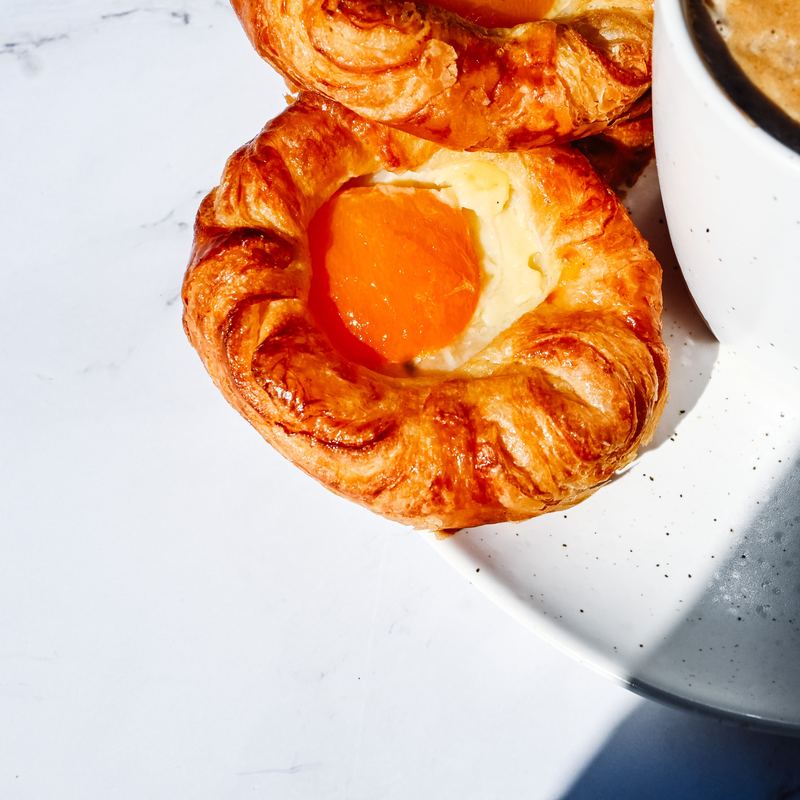 A circular apricot crown pastry with custard and glazed apricot